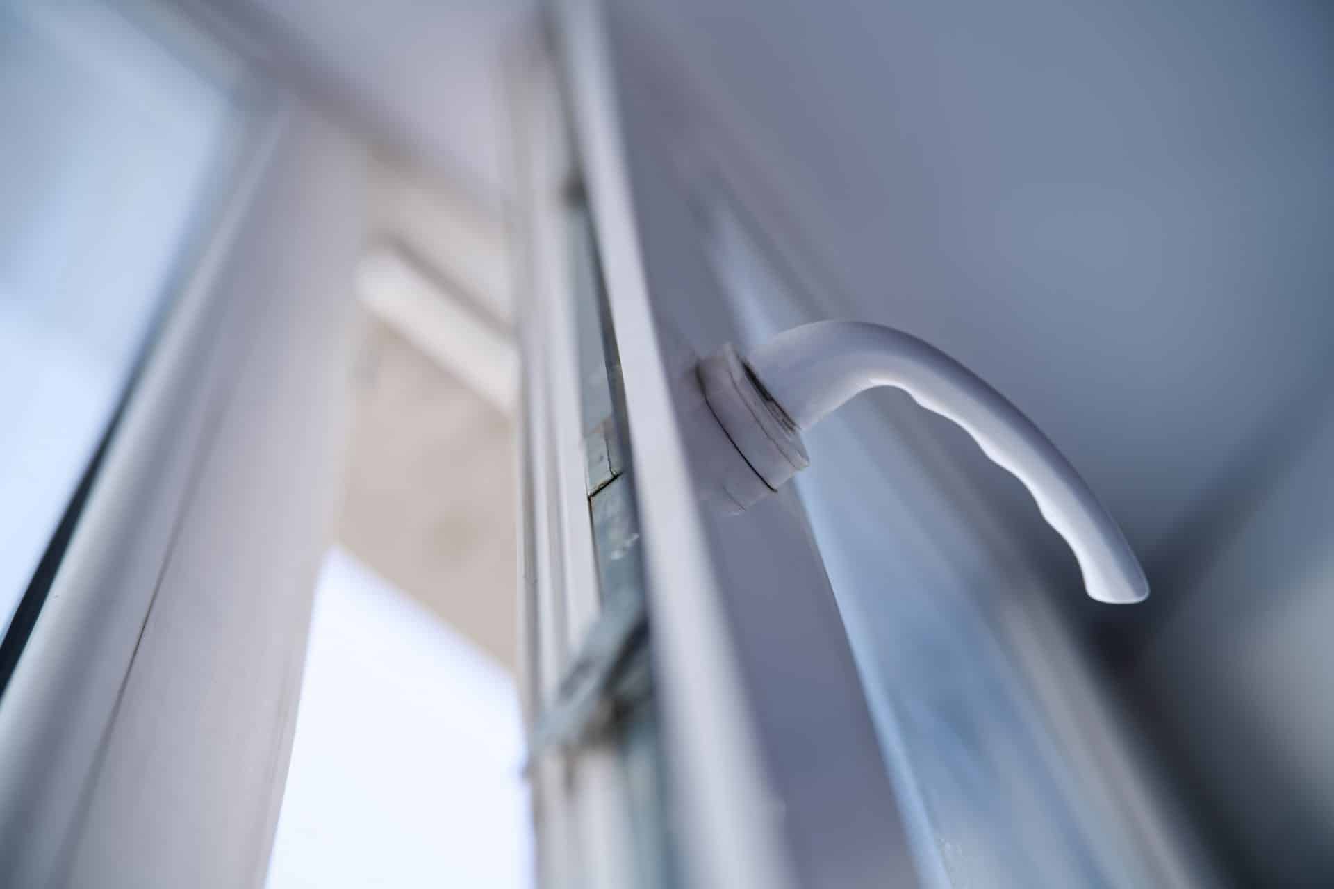 window-lock-4 Open white plastic window handle on a frame. Concept of airing the room for fresh air ventilation. Close up low angle view with selective focus. Photo